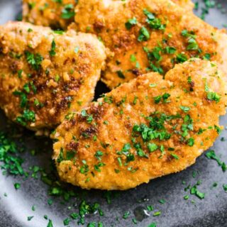 Cooked pork chops piled on plate.