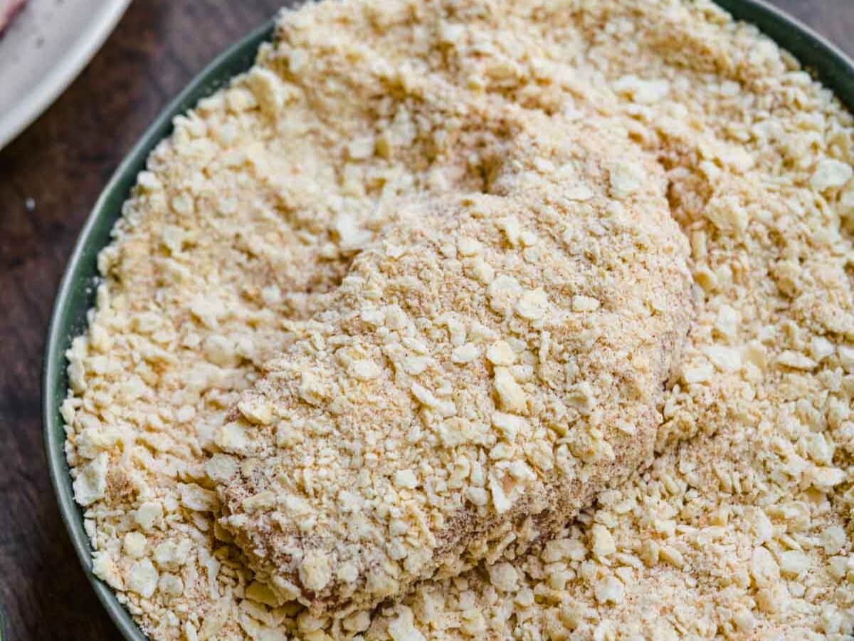 Pork chop coated in crumbs in crumb coat bowl.