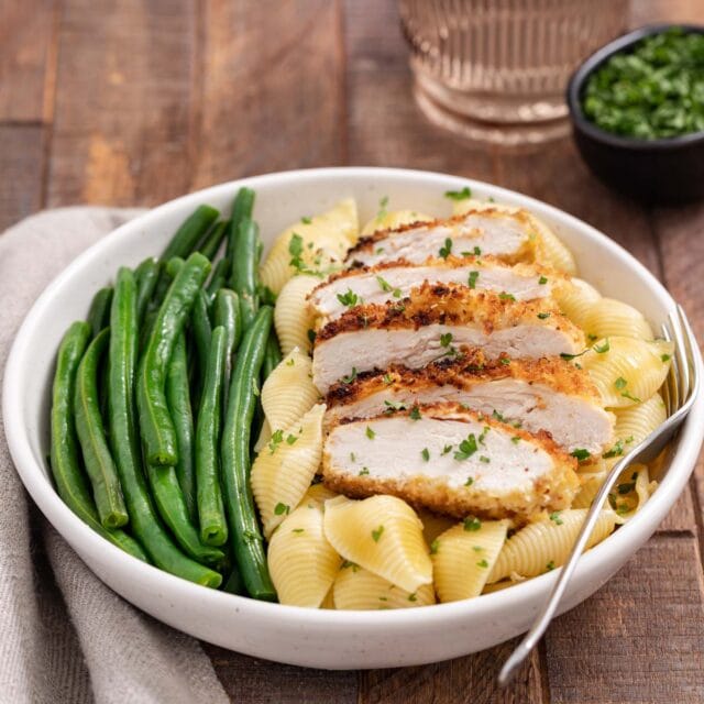 Chicken Cutlets sliced on shell pasta with green beans in large pasta bowl