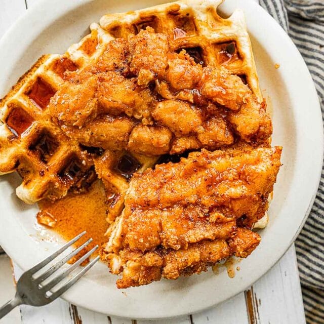 Crispy chicken served over waffle on a plate with a fork 4x3