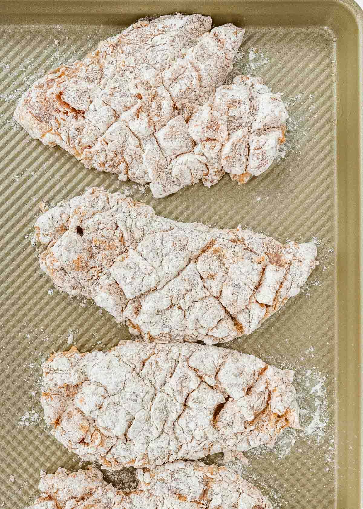 Chicken coated in flour on a tray