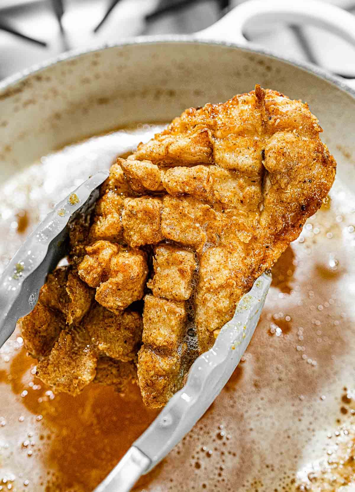 Crispy fried chicken in tongs