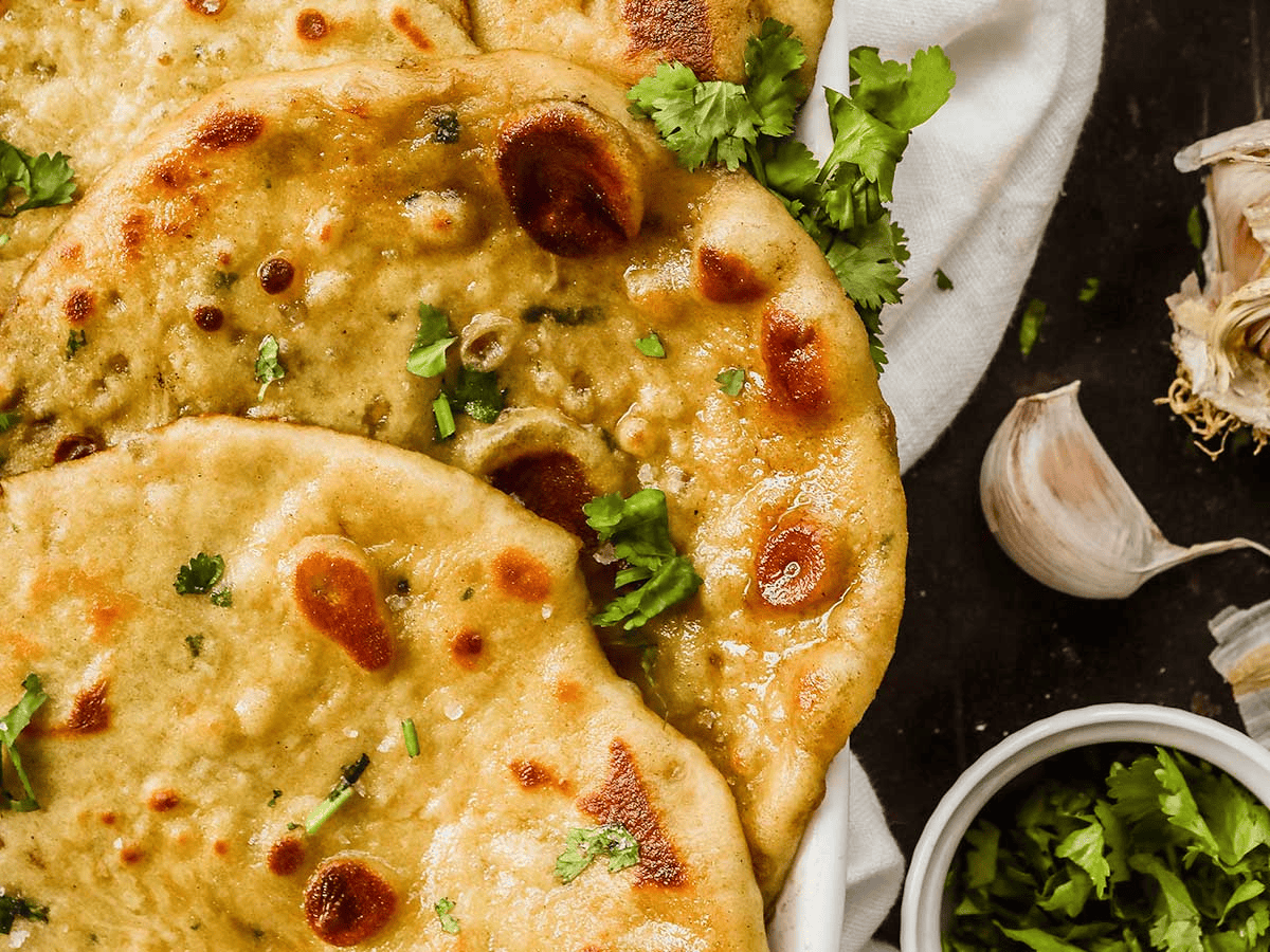 close up of thin bread with green garnish and garlic on the table