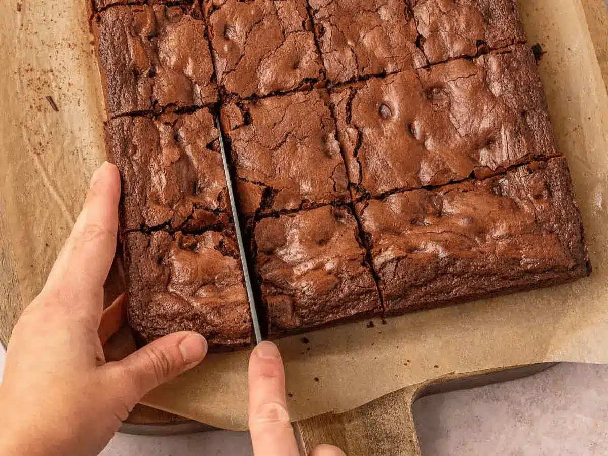 Brownies in baking dish being cut into squares