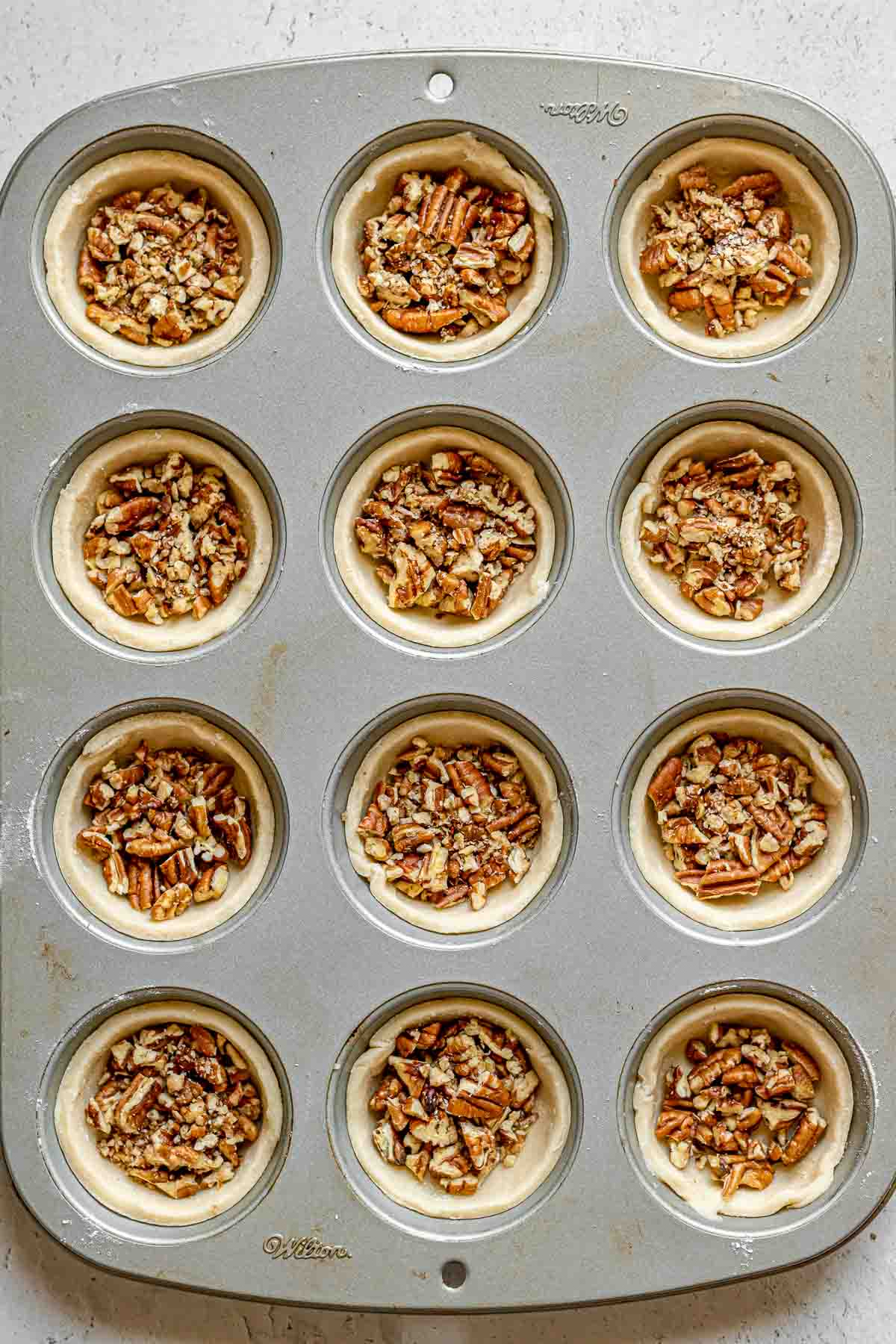 Pecan Butter Tarts pecans on tart shells in muffin tin