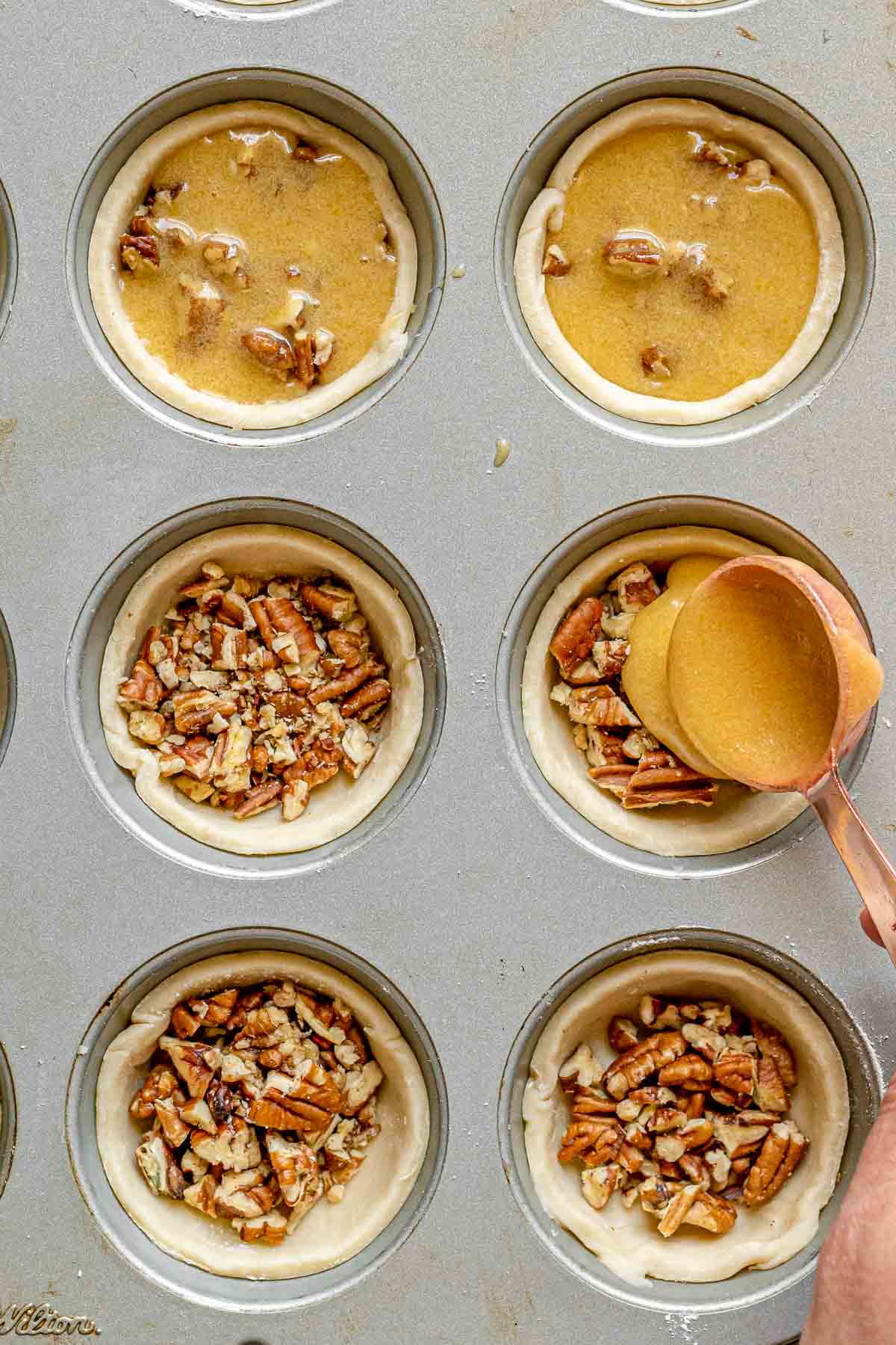Pecan Butter Tarts spooning filling mixture over pecans in tart shells in muffin tin