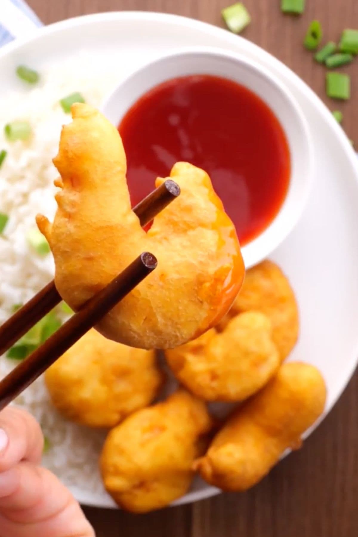 Shrimp Tempura in bowl with rice and sauce, chopstick holding piece