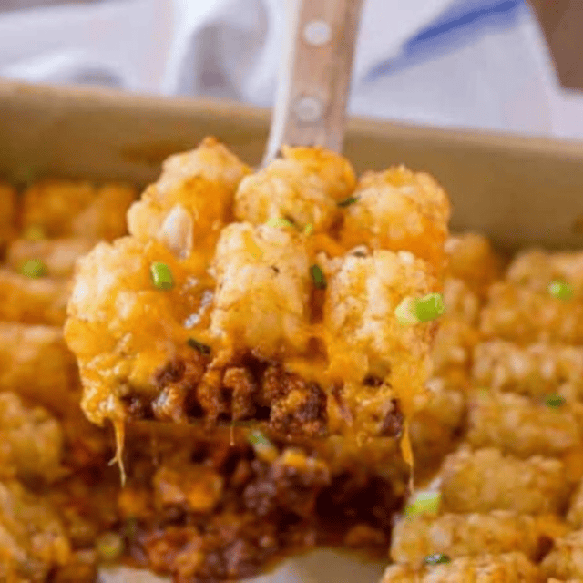 Casserole being scooped out of baking dish with spatula