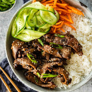 Bowl of cooked beef bulgogi over rice with veggies.