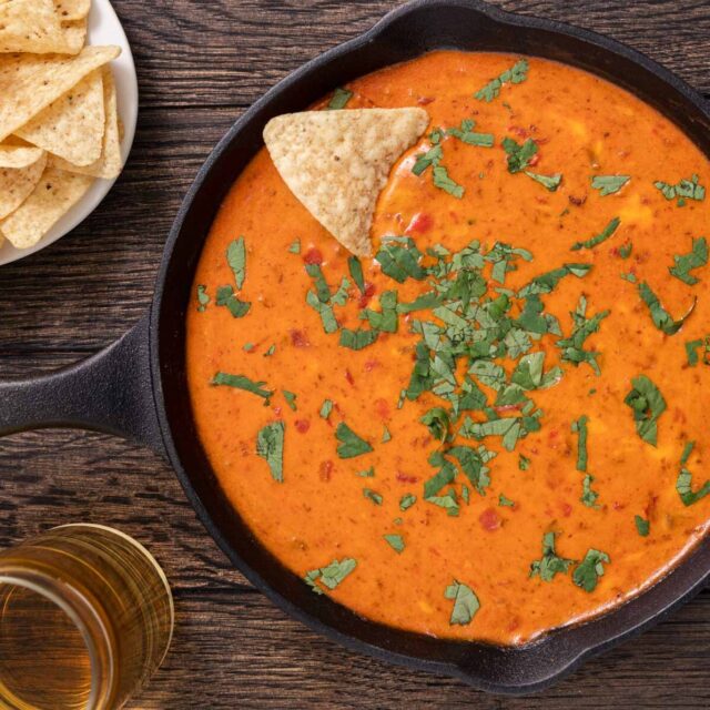 Dip in skillet, bowl of chips, a glass of beer