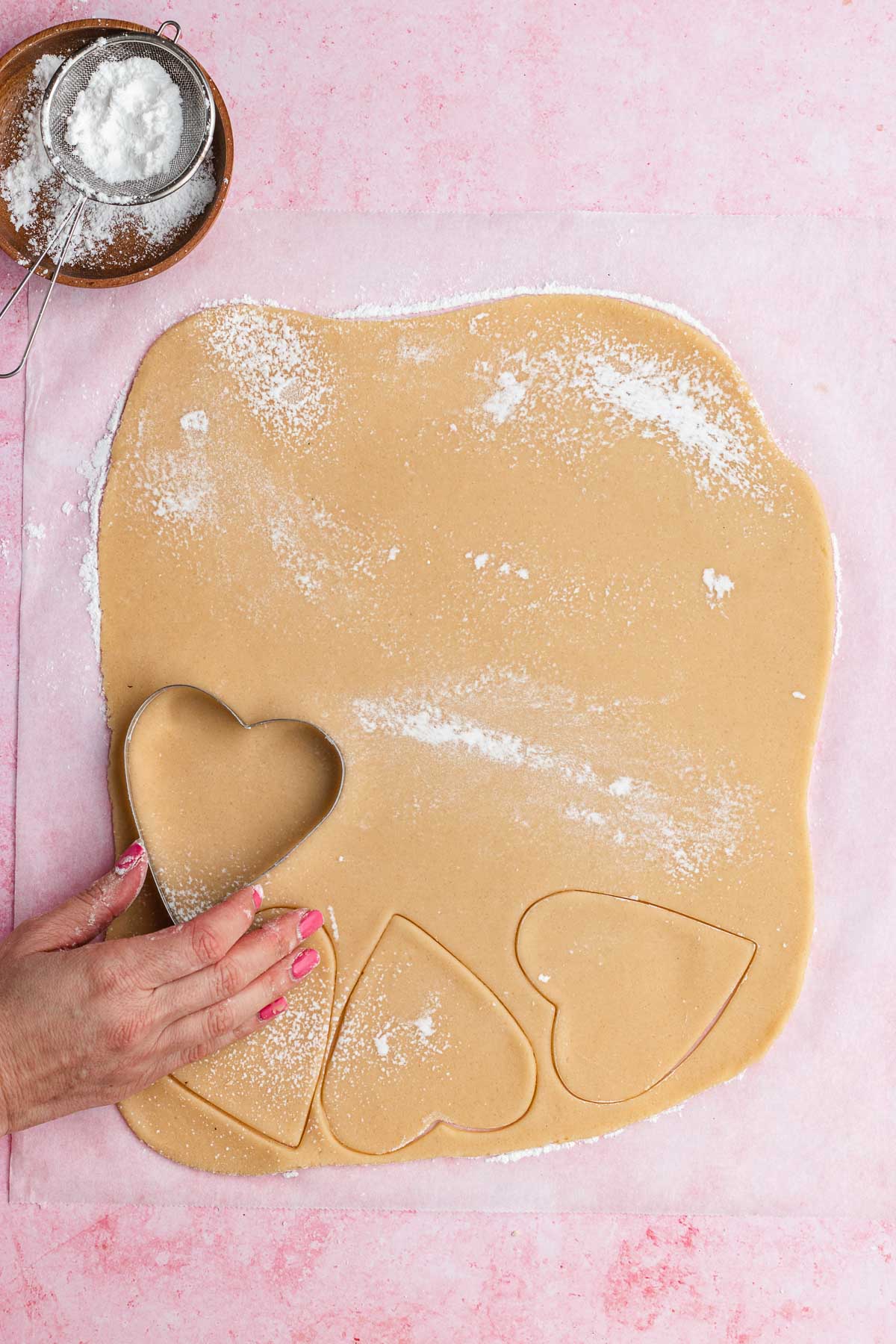 cutting shapes into flattened dough with heart shaped cutter