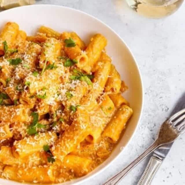 Pasta in bowl topped with Parmesan cheese and parsley