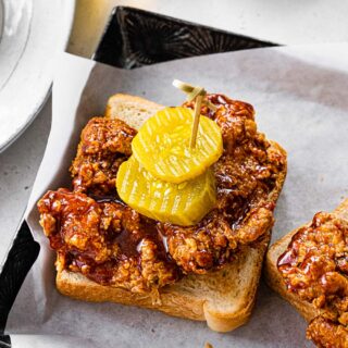 Fried chicken thighs on bread with pickles.