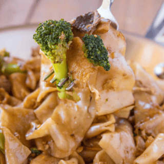 Fork with broccoli and noodles over finished stir fried noodle dish.