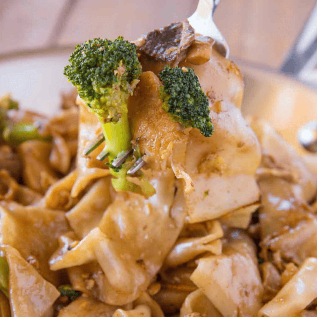 Fork with broccoli and noodles over finished stir fried noodle dish.