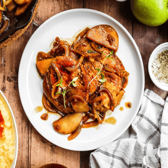 Top view of meat , apple and onions on a white plate