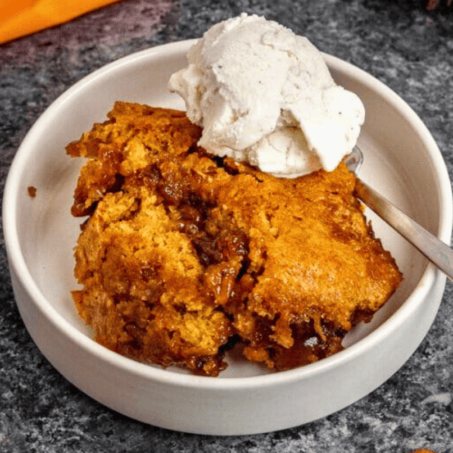 Cobbler in white bowl with spoon and ice cream on top