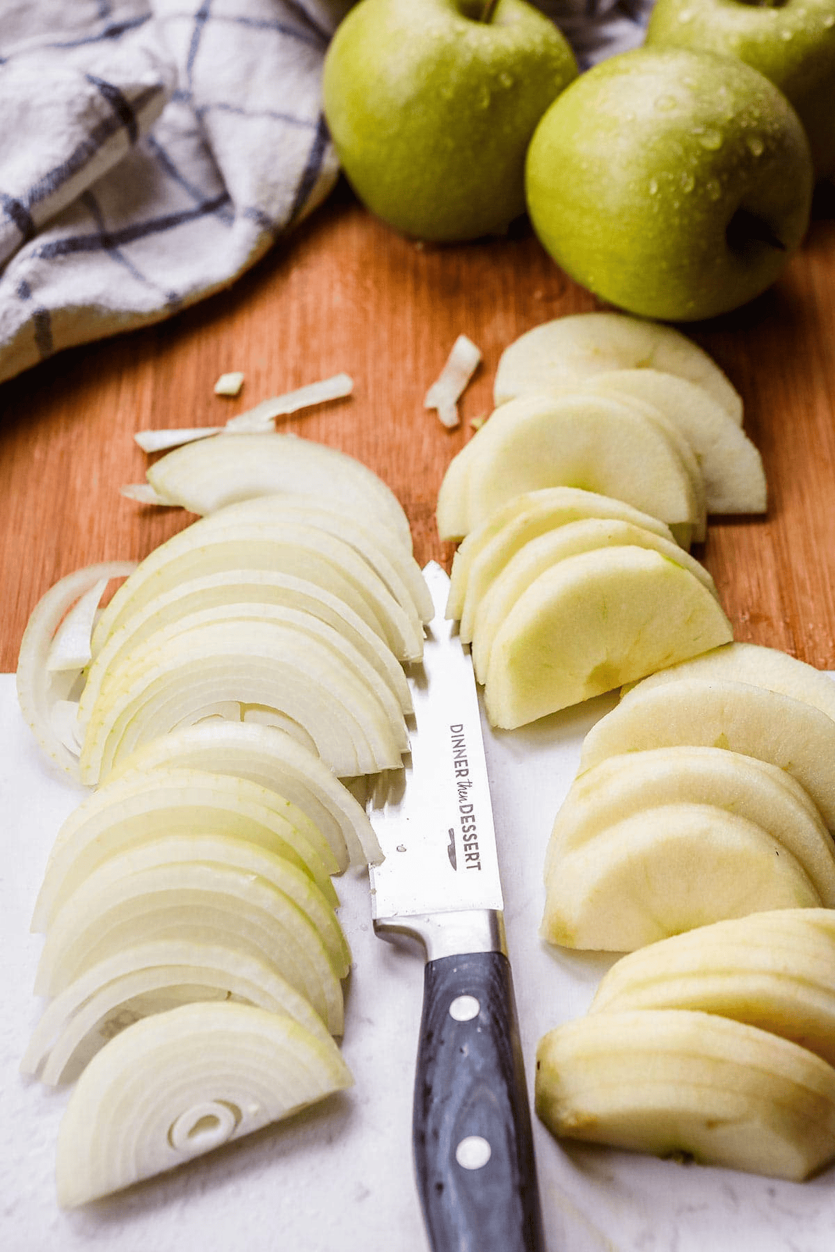 Sliced onions, apples, and a knife on a cutting board