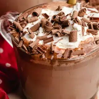 Mug with hot cocoa, topped with whipped cream and candy shavings.