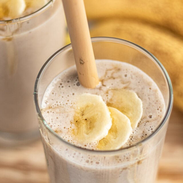 Glass with blended drink, topped with banana slices.
