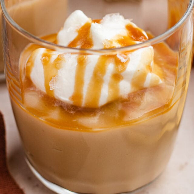 Small glass filled with pudding, and topped with whipped cream.