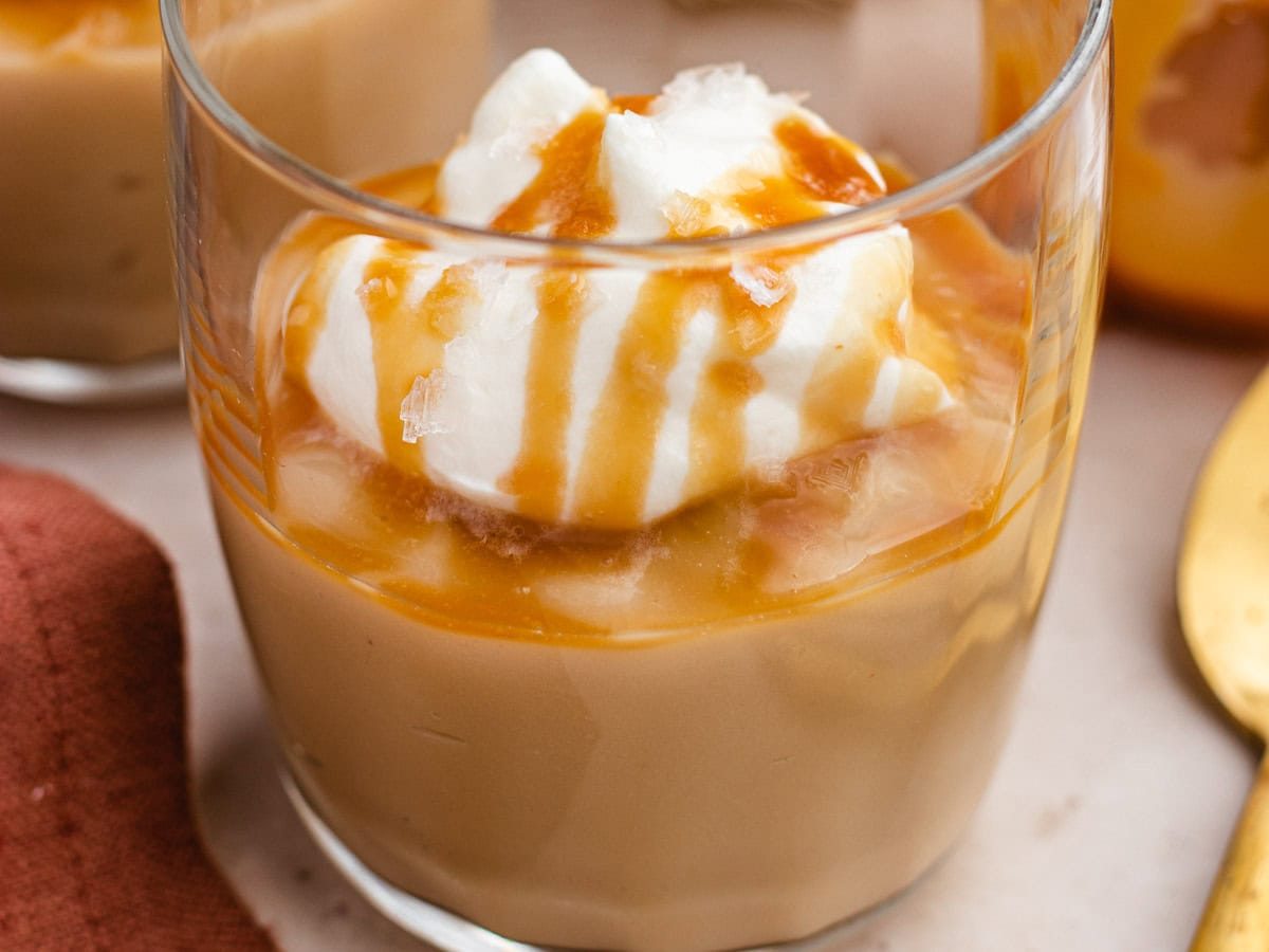 Small glass filled with pudding, and topped with whipped cream.