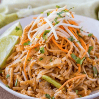 noodles and chicken topped with carrots, bean sprouts, cilantro, and served with a lime