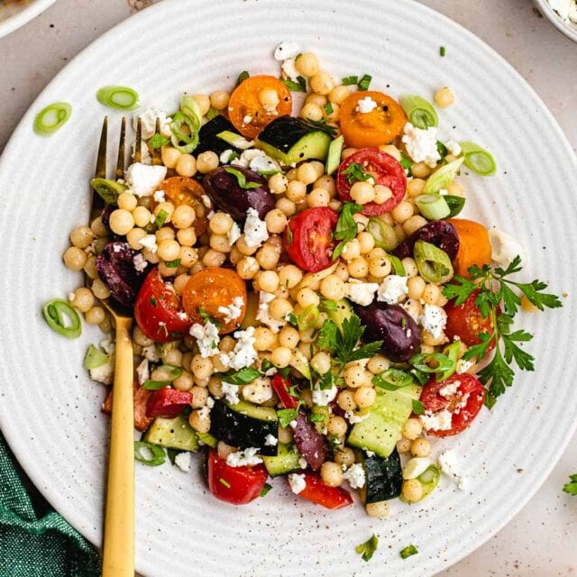 Dressed couscous and vegetables on plate with fork.