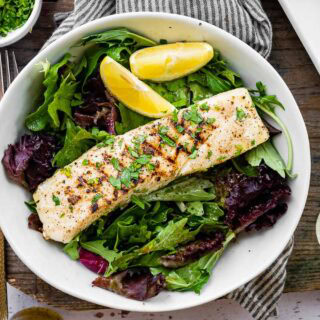 Grilled halibut on dinner plate with greens.