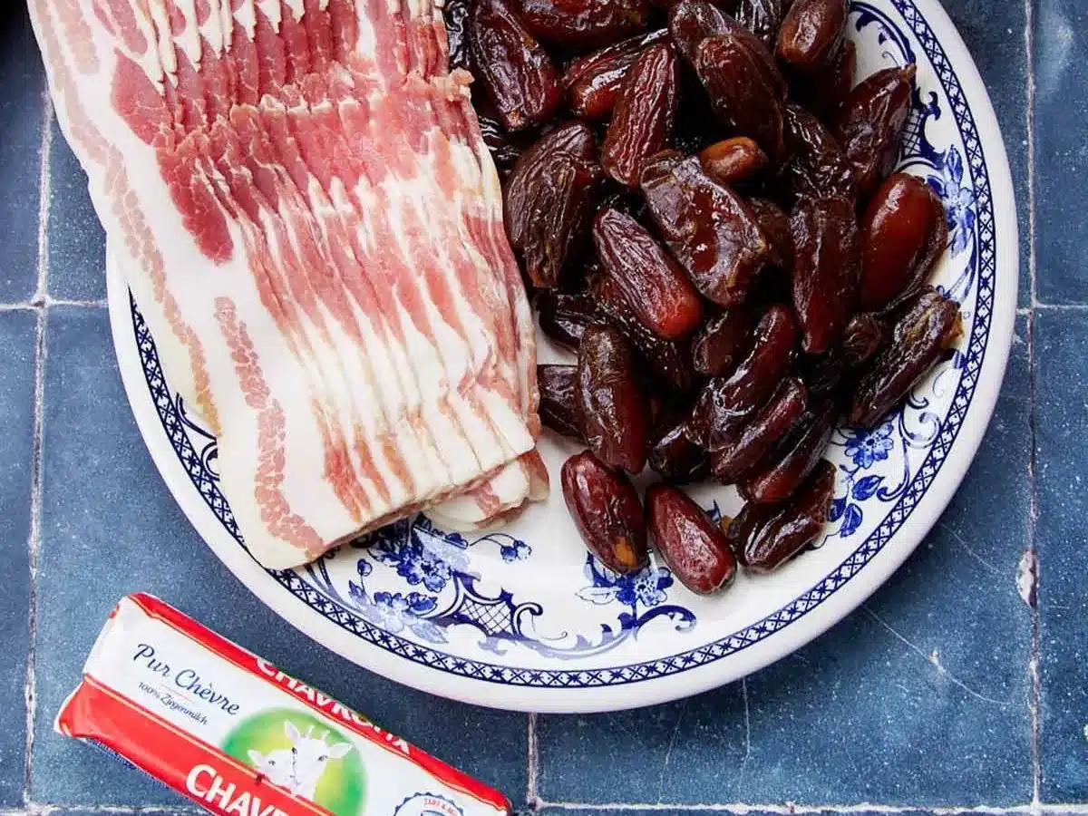 Goat cheese, bacon strips, and dates on countertop.