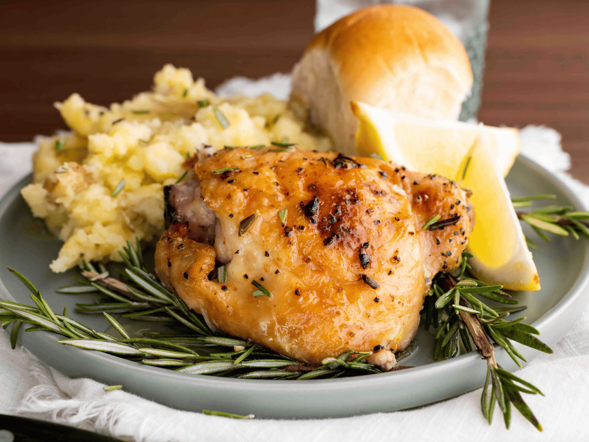 Plate with cooked poultry, sides, and a roll. Ready to eat