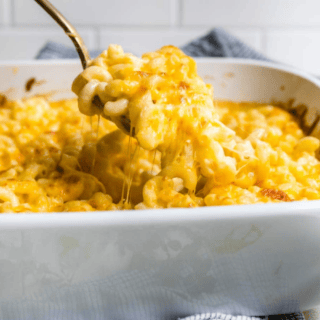 Mac and cheese in a white baking dish with spoon taking bite