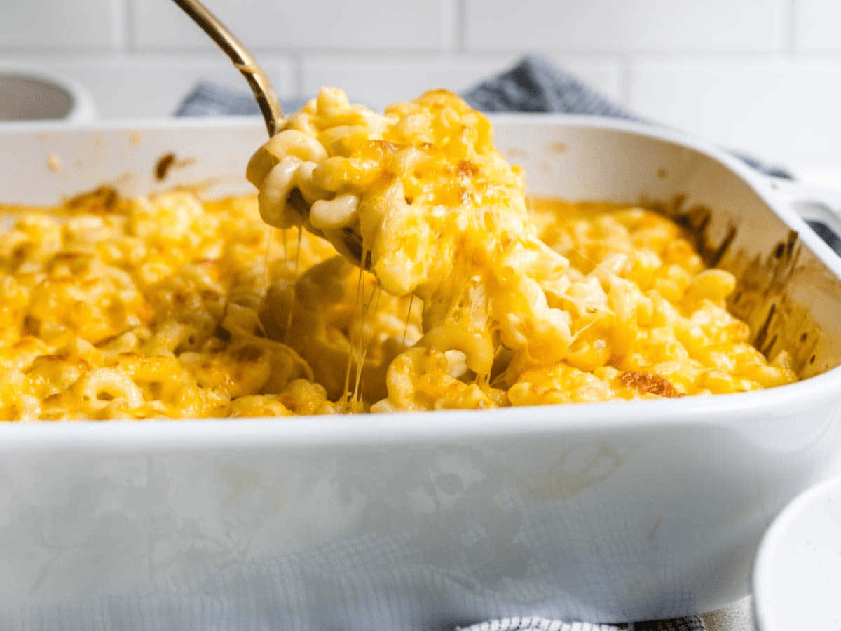 Mac and cheese in a white baking dish with spoon taking bite