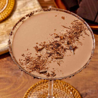 Creamy cocktail garnished with chocolate shavings in martini glass.