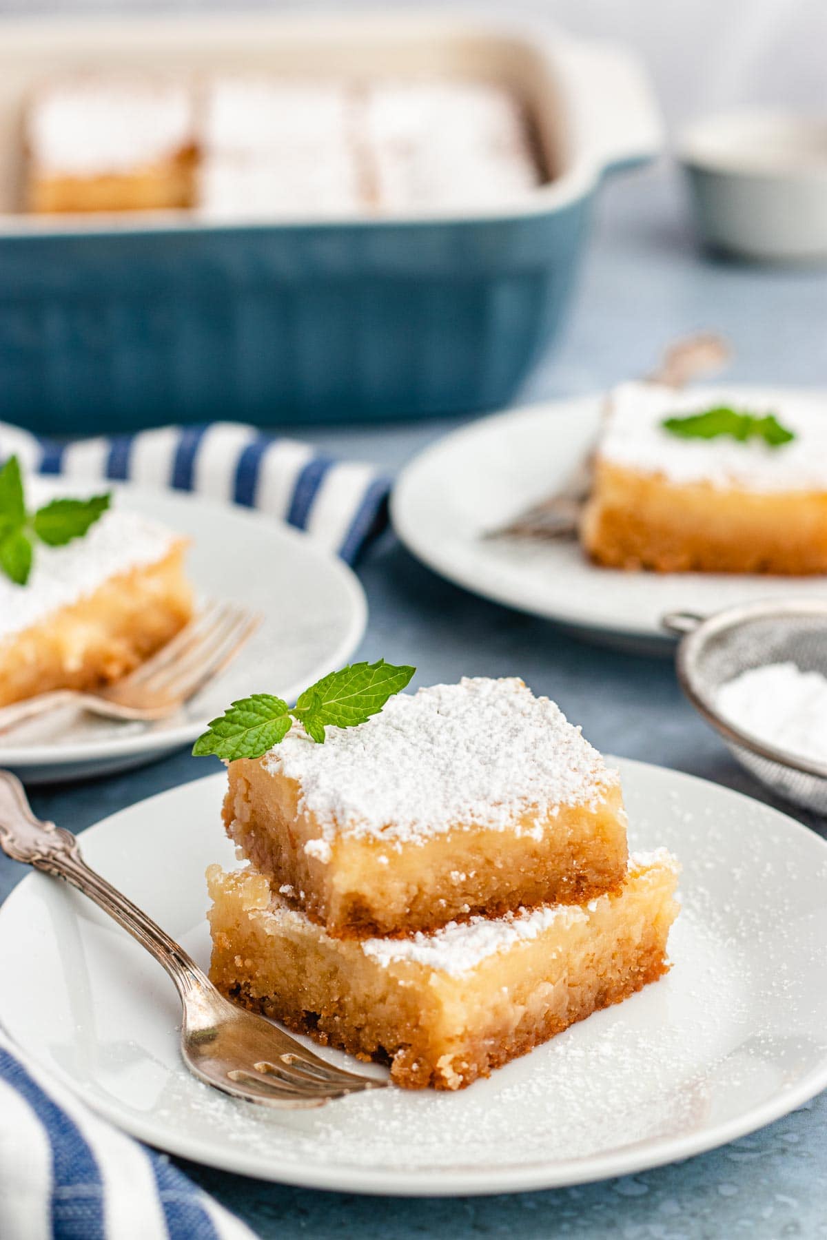 Two slices of Gooey Butter cake on a plate with a fork. Full Gooey Butter Cake pan in the background.