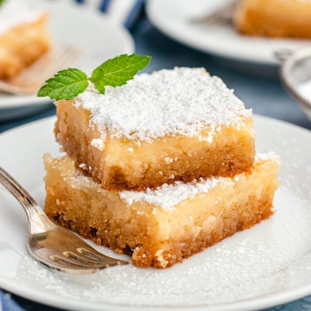 Gooey Butter Cake on a plate with a fork and topped with powdered sugar.