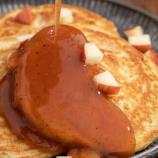 Pancakes with diced apple chunks, and syrup.