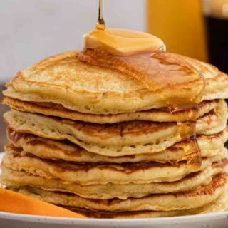 Syrup being poured on top of griddle cakes.
