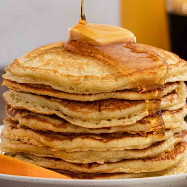 Syrup being poured on top of griddle cakes.