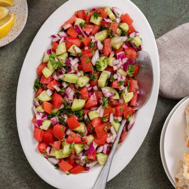 Israeli salad on serving plate with large spoon.