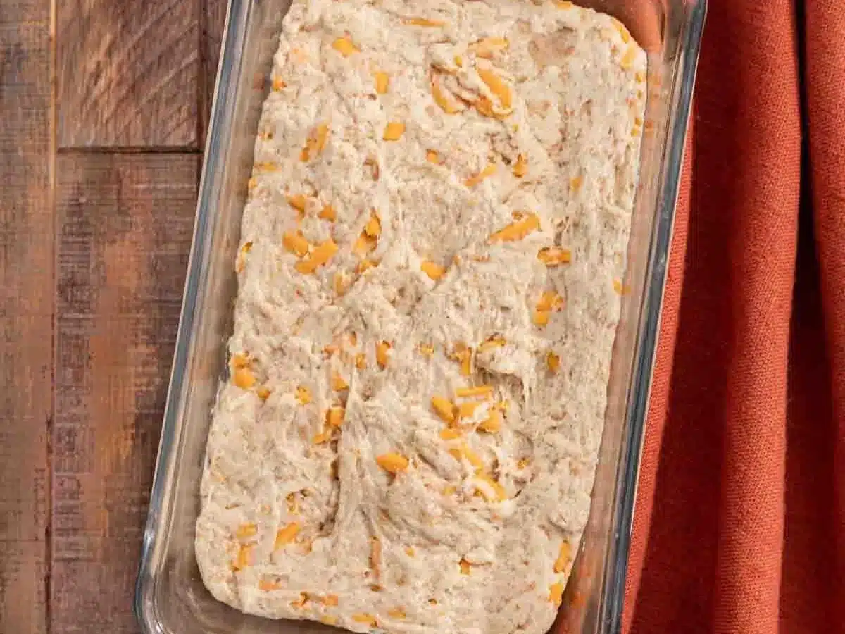 Raw dough with shredded cheese in 9x5 inch pan.