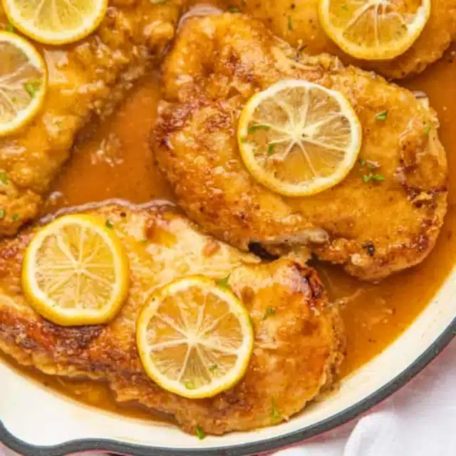Chicken in pan with sauce and lemons