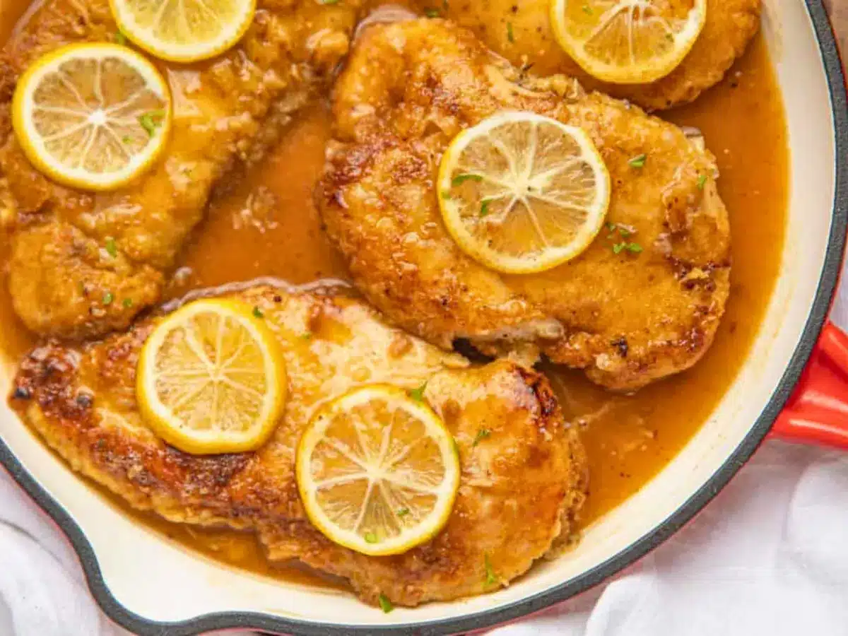 Chicken in pan with sauce and lemons