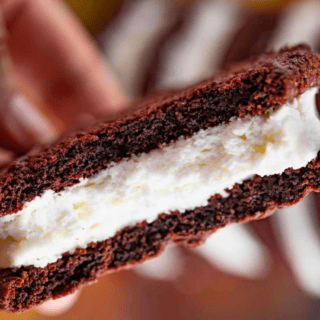 chocolate sandwich with white filling in hand bitten in half