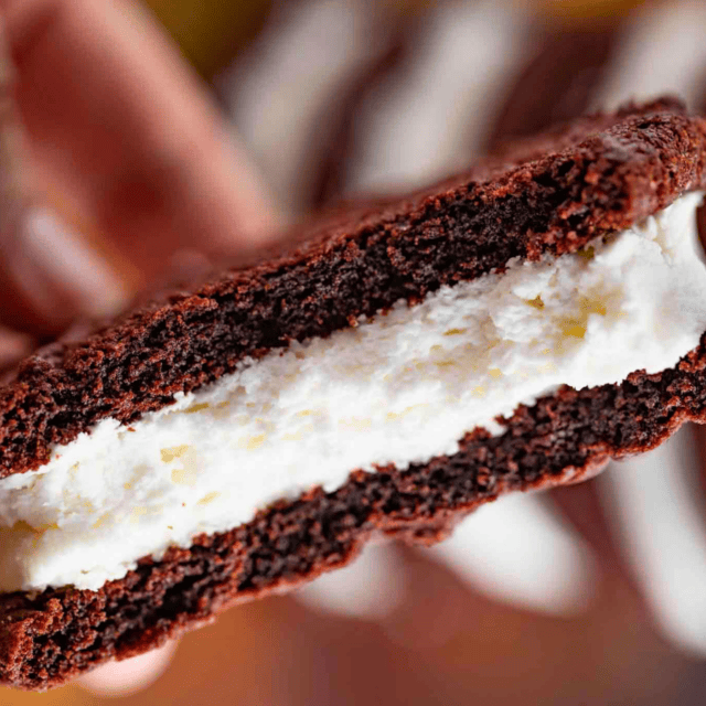 chocolate sandwich with white filling in hand bitten in half