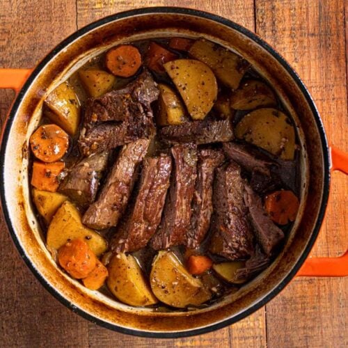 Sliced cooked roast in pot with potatoes and carrots