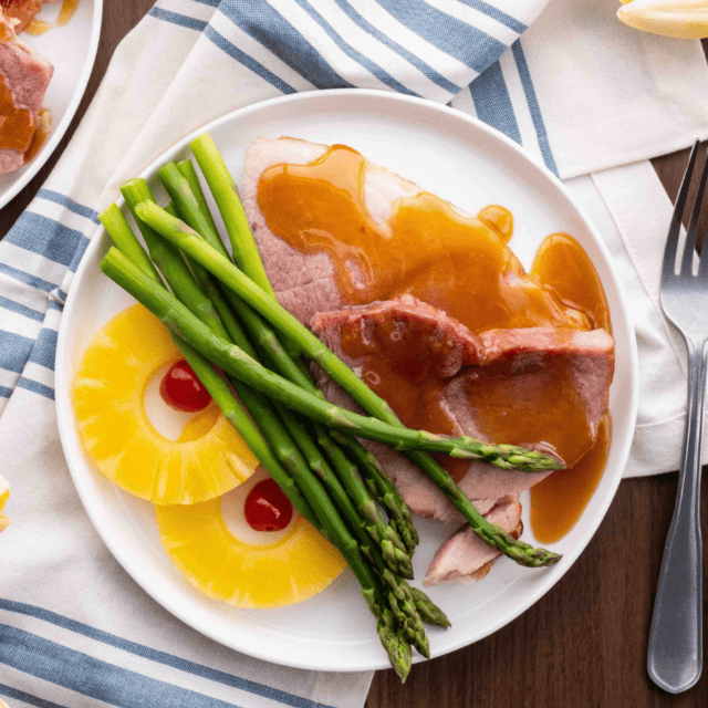 plated ham pieces with pineapple rings and asparagus