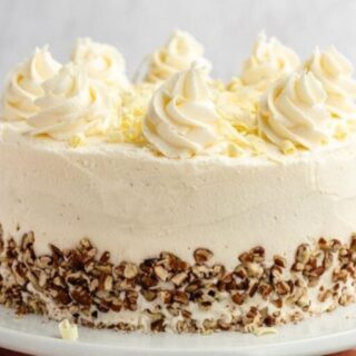 Cake on a platter garnished with pecans and frosting.