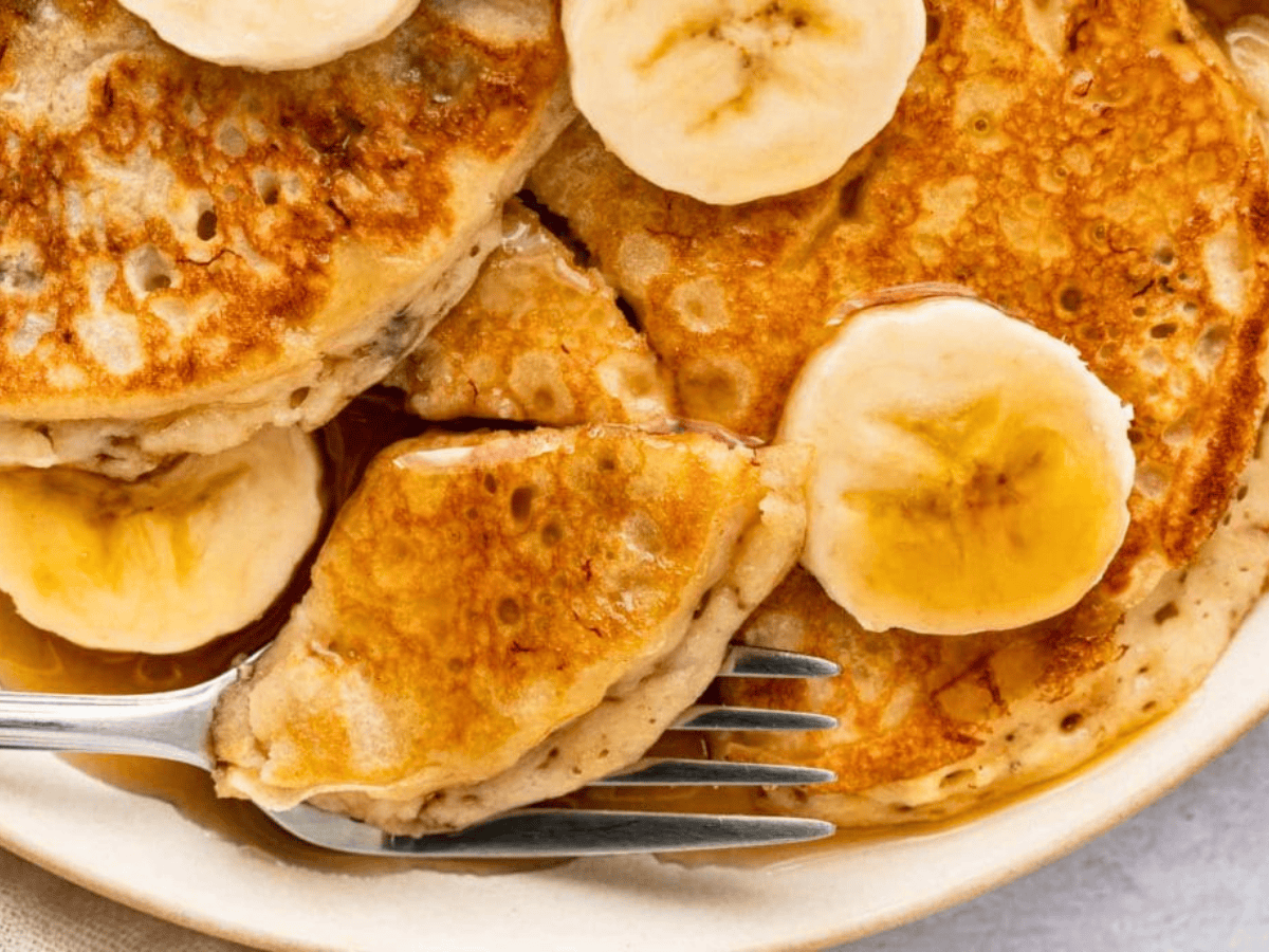Plate of pancakes with banana slices and fork