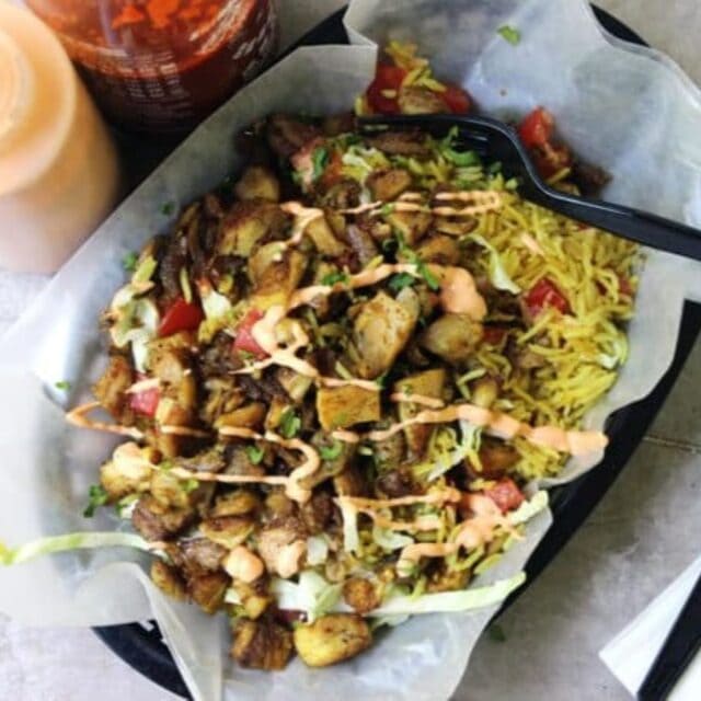 Bowl with chicken, rice, and spices with a fork and sauce.